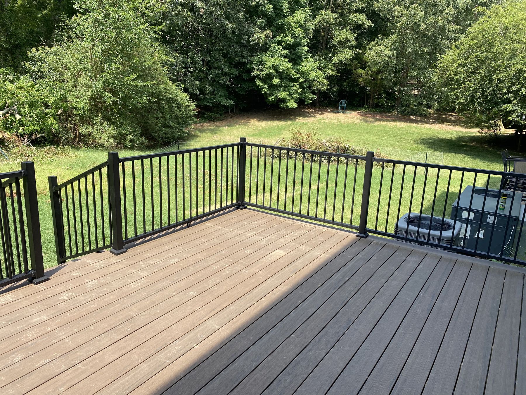 A finished composite deck with black aluminum railing overlooking a green Triangle backyard