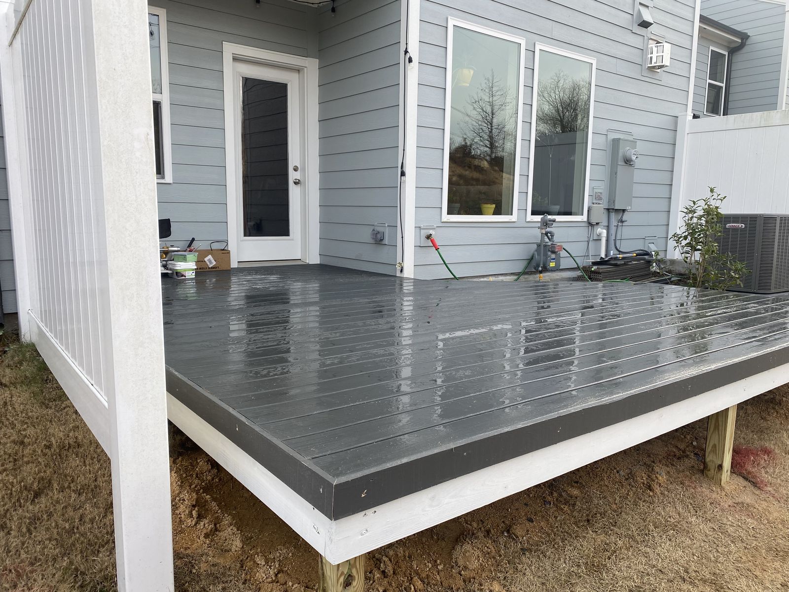 Composite deck corner with black aluminum railing and green yard