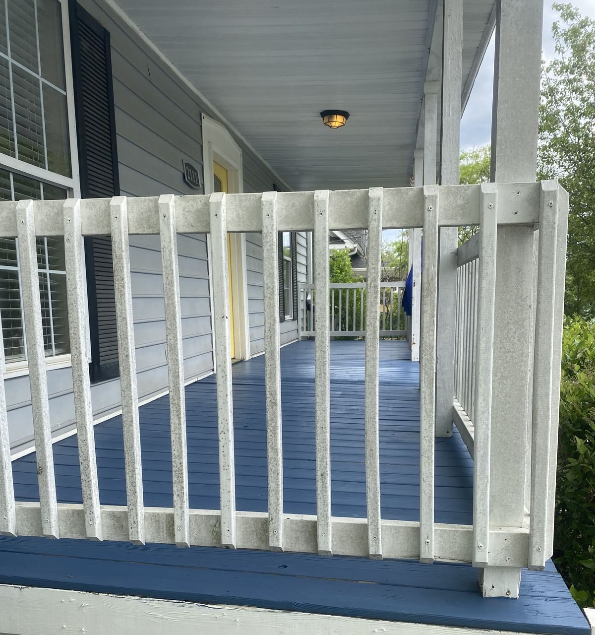 Covered porch with white railing and painted deck