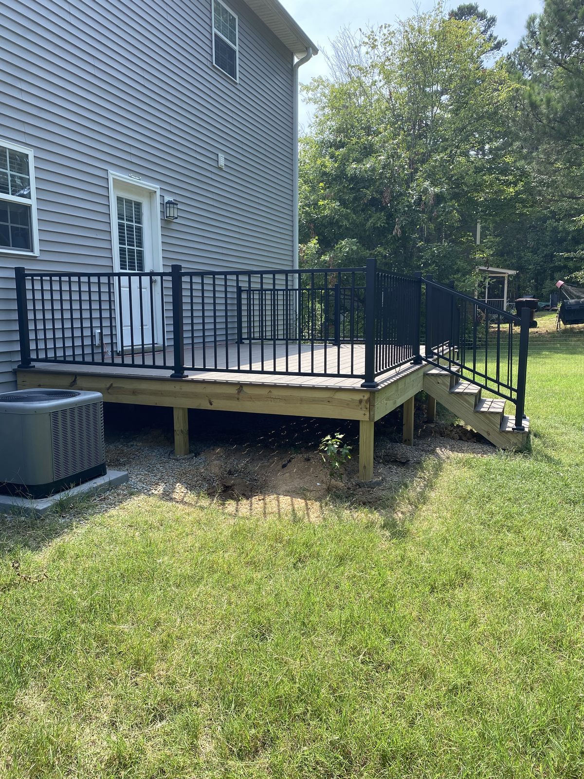 Backyard deck with black aluminum railing on a green lawn