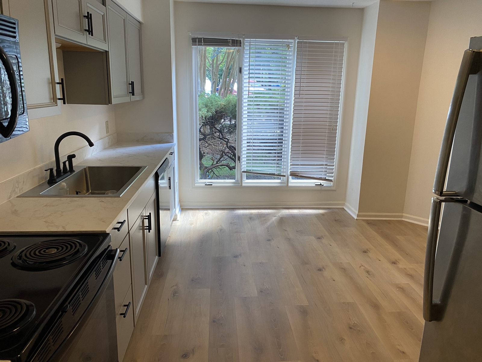 Renovated kitchen with white cabinets, quartz counters and wood flooring