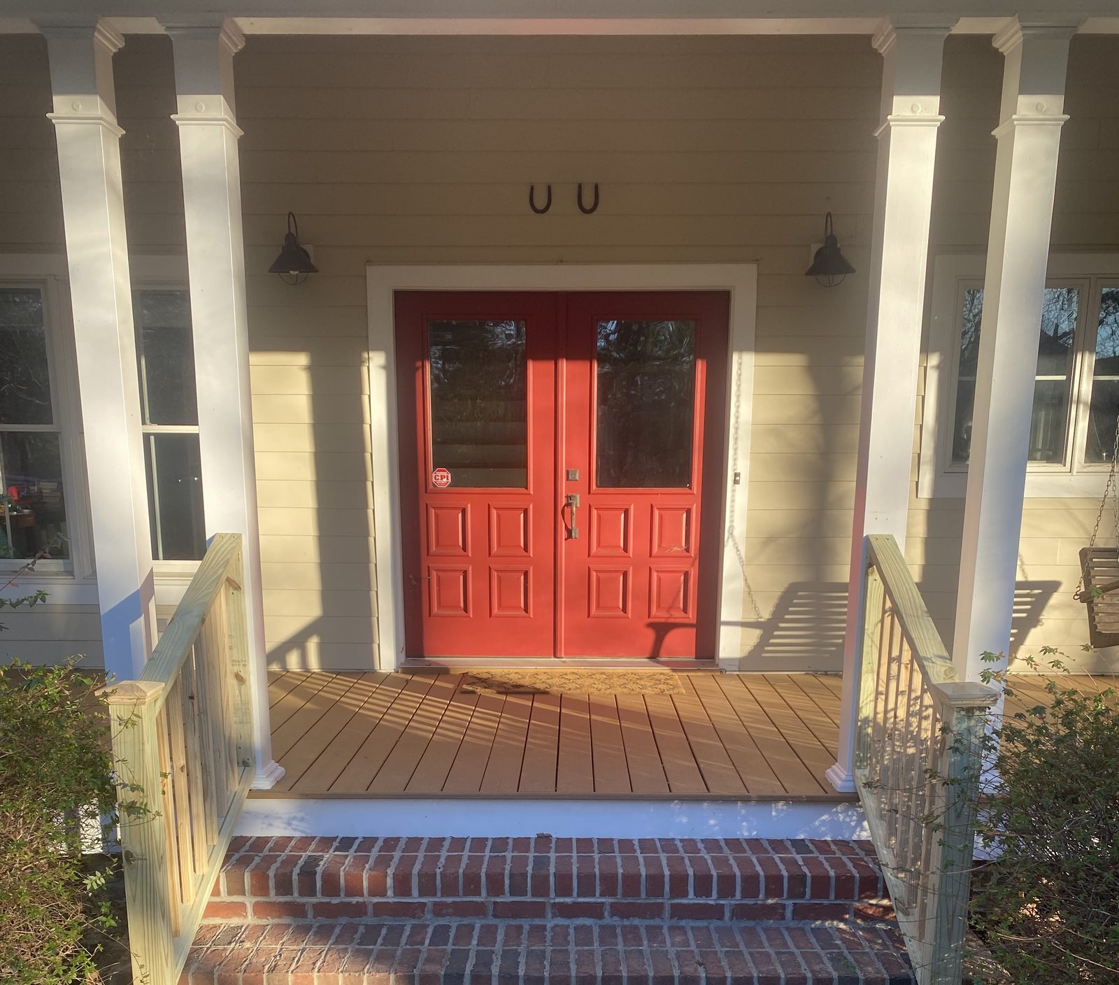 Refinished front porch with red double doors and brick steps